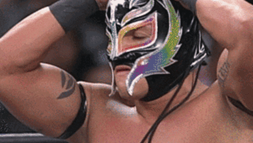 A Wrestler Is Wearing A Mask With A Rainbow Design On His Face . GIF