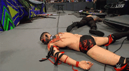 A Wrestler Laying On The Ground With The Word Live On The Screen GIF