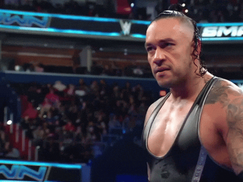A Wrestler Stands In Front Of A Sign That Says Sinclair GIF