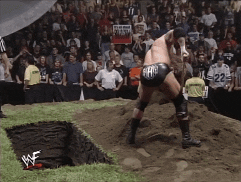 a wrestler wearing a black shorts with the word gear on it stands in the dirt