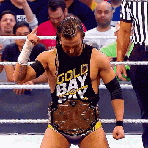 A Wrestler Wearing A Gold Bay Shirt Stands In The Ring GIF