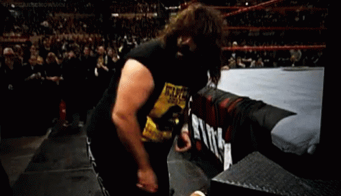 A Wrestler Wearing A Wanted Shirt Is Standing In A Ring . GIF