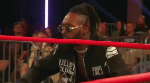 A Wrestler Wearing Sunglasses Is Crawling Through The Ring . GIF