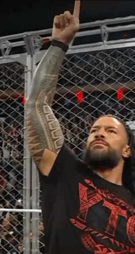 A Wrestler With A Tattoo On His Arm Holds Up His Fist In The Air GIF