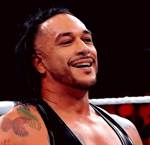 A Wrestler With A Tattoo On His Arm Is Smiling GIF