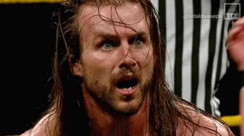 A Wrestler With Long Hair And A Beard Is Making A Funny Face . GIF