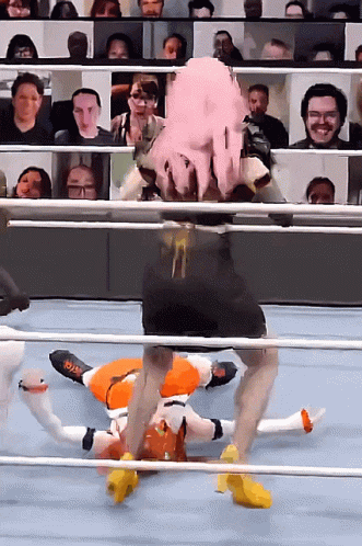 A Wrestler With Pink Hair Is Laying On The Ground In A Ring GIF