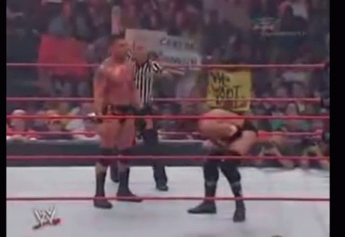 A Wrestling Match Is Being Held In A Ring With A Referee Standing Behind It . GIF