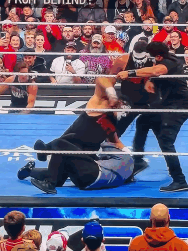 A Wrestling Match Is Going On In Front Of A Crowd With One Man Wearing A Shirt That Says ' Biker ' GIF
