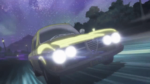 A Yellow Alfa Romeo Is Driving Down A Road At Night With Its Headlights On GIF