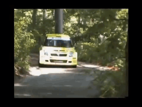 A Yellow And White Car Is Driving Down A Road Surrounded By Trees GIF