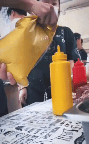 A Yellow Bottle Of Mustard Is Sitting On A Table GIF