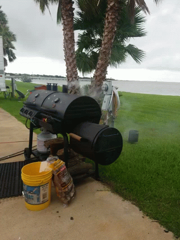 A Yellow Bucket With The Word Fire On It Sits On A Sidewalk Next To A Grill GIF