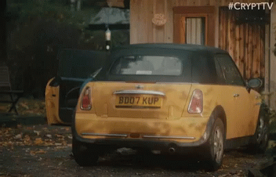 A Yellow Car With The License Plate B007 Kup Is Parked In Front Of A Wooden Building GIF