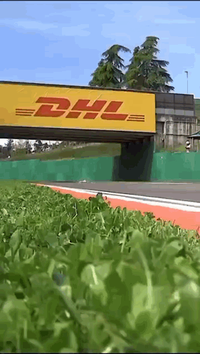 A Yellow Dhl Sign Is Above A Grassy Area GIF