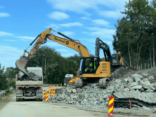 A Yellow Excavator With The Word Rustad On The Side GIF