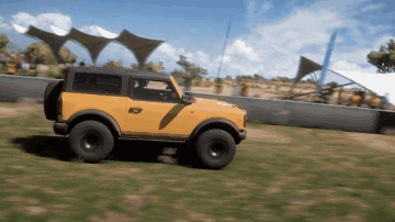 A Yellow Jeep Is Driving Through A Grassy Area GIF