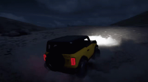 A Yellow Jeep With A Red Tail Light Is Driving On A Dirt Road GIF