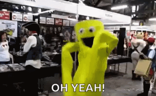 A Yellow Mascot In A Costume Is Dancing In A Room With People . GIF