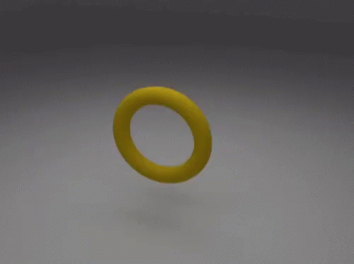 A Yellow Object With A Hole In The Middle Is Sitting On A White Surface GIF