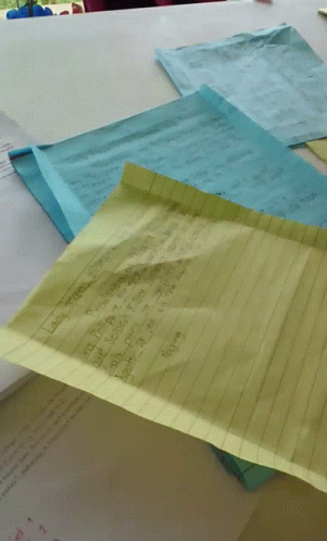 A Yellow Piece Of Paper Is Laying On Top Of A Pile Of Paper GIF