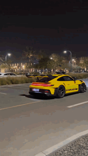 A Yellow Porsche 911 Gt3 Rs Is Driving Down A Road At Night GIF
