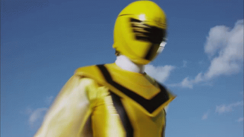 A Yellow Power Ranger Stands In Front Of A Blue Sky With Clouds GIF