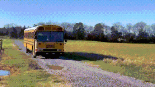 A Yellow School Bus Driving Down A Dirt Road GIF