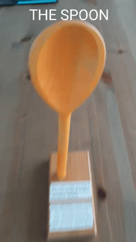 A Yellow Spoon Sitting On Top Of A Wooden Box With The Words " The Spoon " Below It GIF
