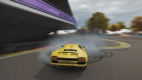 A Yellow Sports Car Is Drifting On A Track With Smoke Coming Out Of The Tires GIF