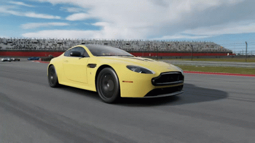 A Yellow Sports Car Is Driving Down A Track GIF