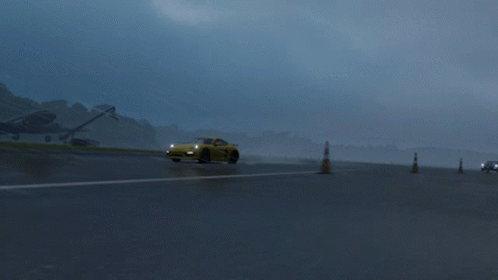 A Yellow Sports Car Is Driving On A Wet Road GIF