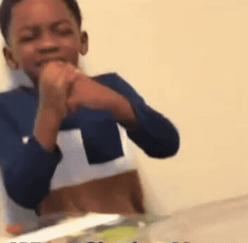 A Young Boy In A Blue Shirt Is Sitting At A Table With His Hands Folded . GIF