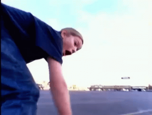 a young boy in a blue shirt is standing in a parking lot