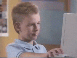 A Young Boy In A Blue Shirt Is Using A Laptop Computer GIF