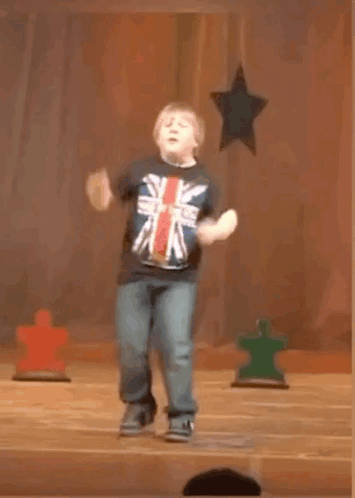 A Young Boy In A British Flag Shirt Is Jumping In The Air GIF