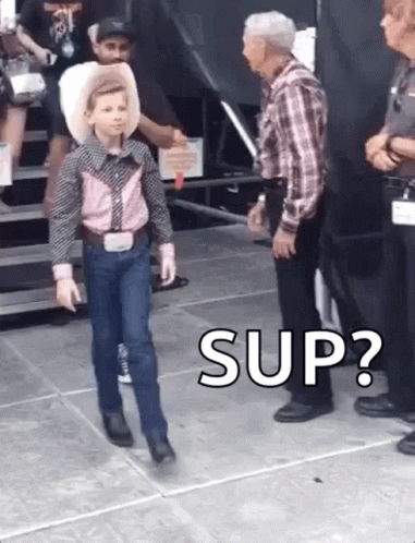 A Young Boy In A Cowboy Outfit Is Walking In Front Of A Man In A Plaid Shirt And Says " Sup " . GIF