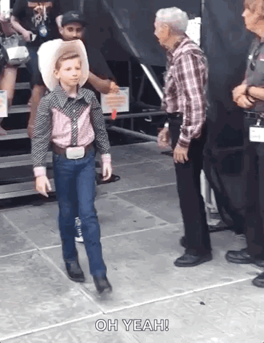 A Young Boy In A Cowboy Outfit Is Walking Towards An Older Man Who Says Oh Yeah . GIF