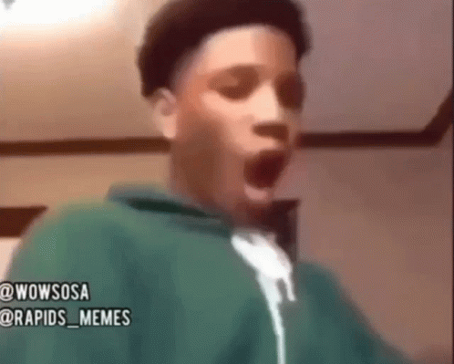 A Young Boy In A Green Hoodie Is Making A Surprised Face . GIF