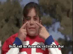 A Young Boy In A Red And White Jersey Is Making A Funny Face With His Hands . GIF