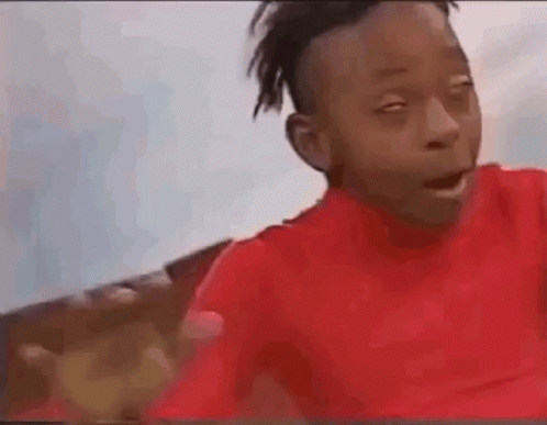 A Young Boy In A Red Shirt Is Making A Funny Face And Waving At The Camera . GIF