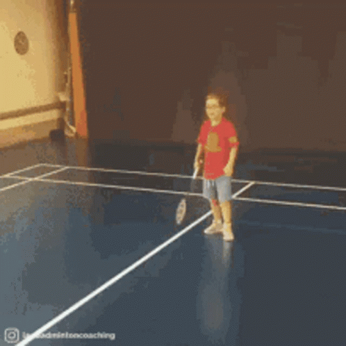 A Young Boy In A Red Shirt Is Playing Badminton On A Blue Court GIF