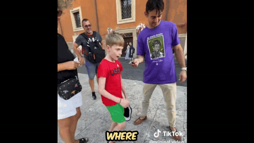 a young boy in a red shirt is standing next to a man in a purple shirt .