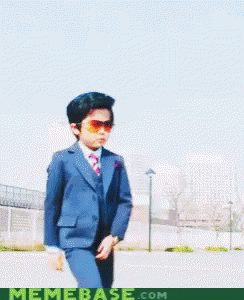 A Young Boy In A Suit And Tie Holds A Pair Of Glasses In Front Of A Memebase.com Logo GIF