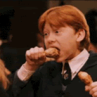 A Young Boy In A Suit And Tie Is Eating A Piece Of Food . GIF