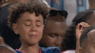 A Young Boy Is Crying In A Crowd Of People At A Sports Game . GIF