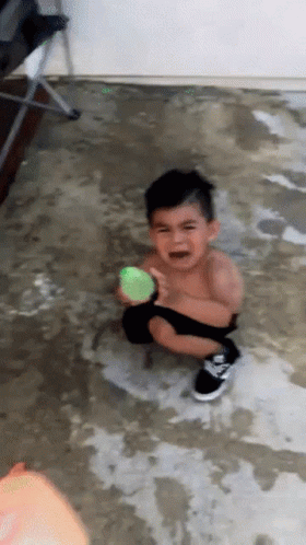 A Young Boy Is Crying While Holding A Ball GIF