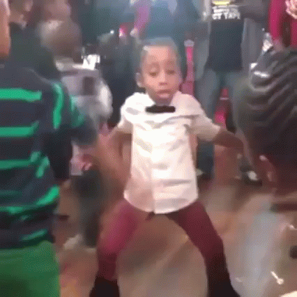 A Young Boy Is Dancing In A Crowd Of People . GIF