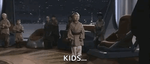 A Young Boy Is Holding A Blue Lightsaber In Front Of A Group Of People . GIF