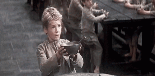 A Young Boy Is Holding A Bowl Of Food In His Hands . GIF